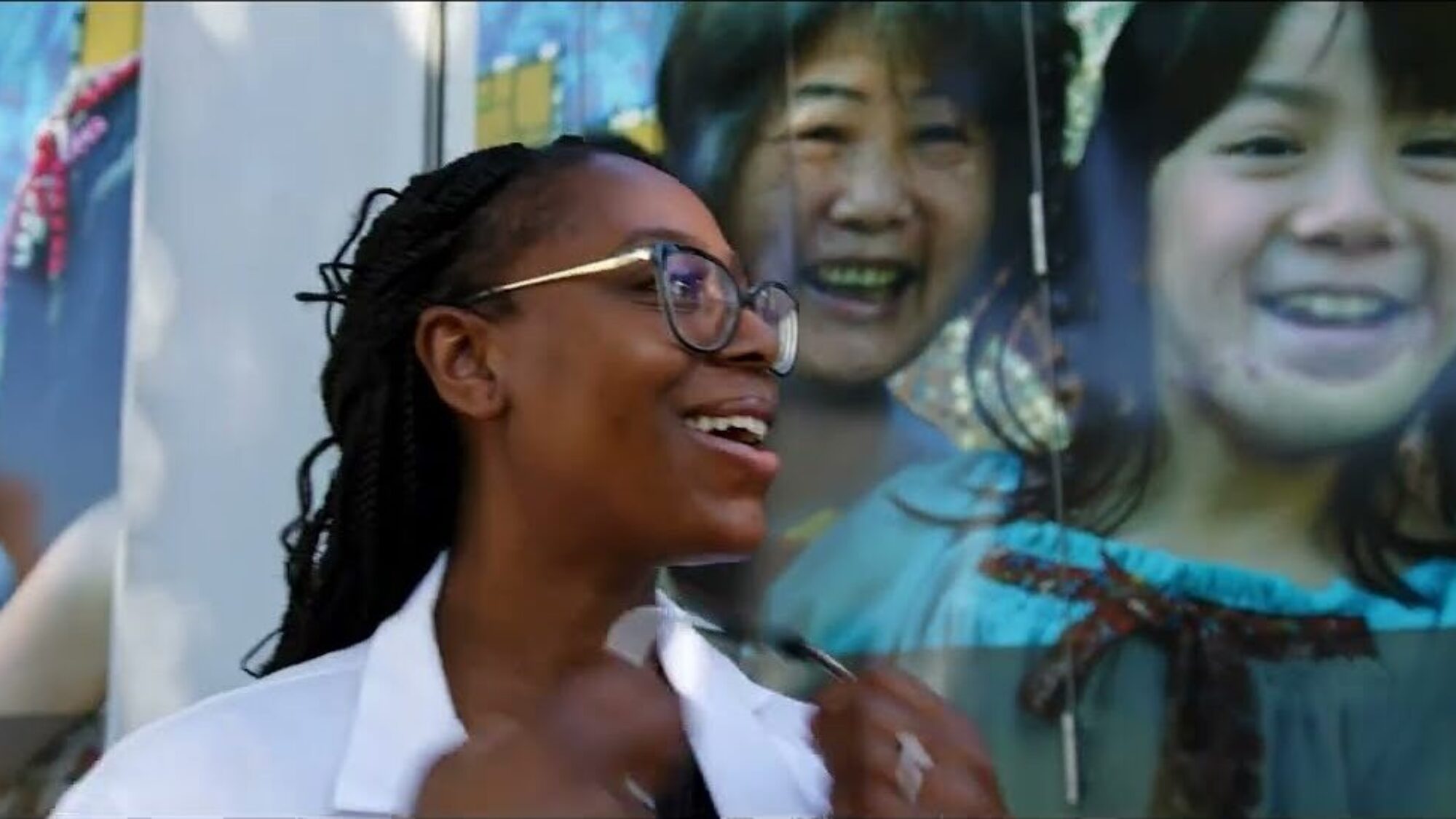video thumbnail of a person smiling in front of street art mural
