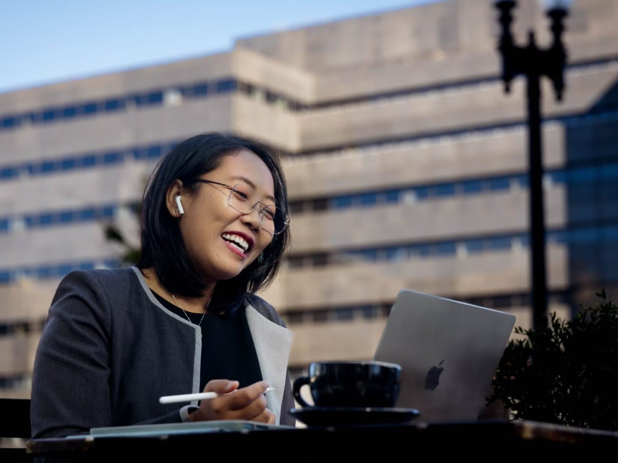 a sitting student smiles as she looks at her laptop