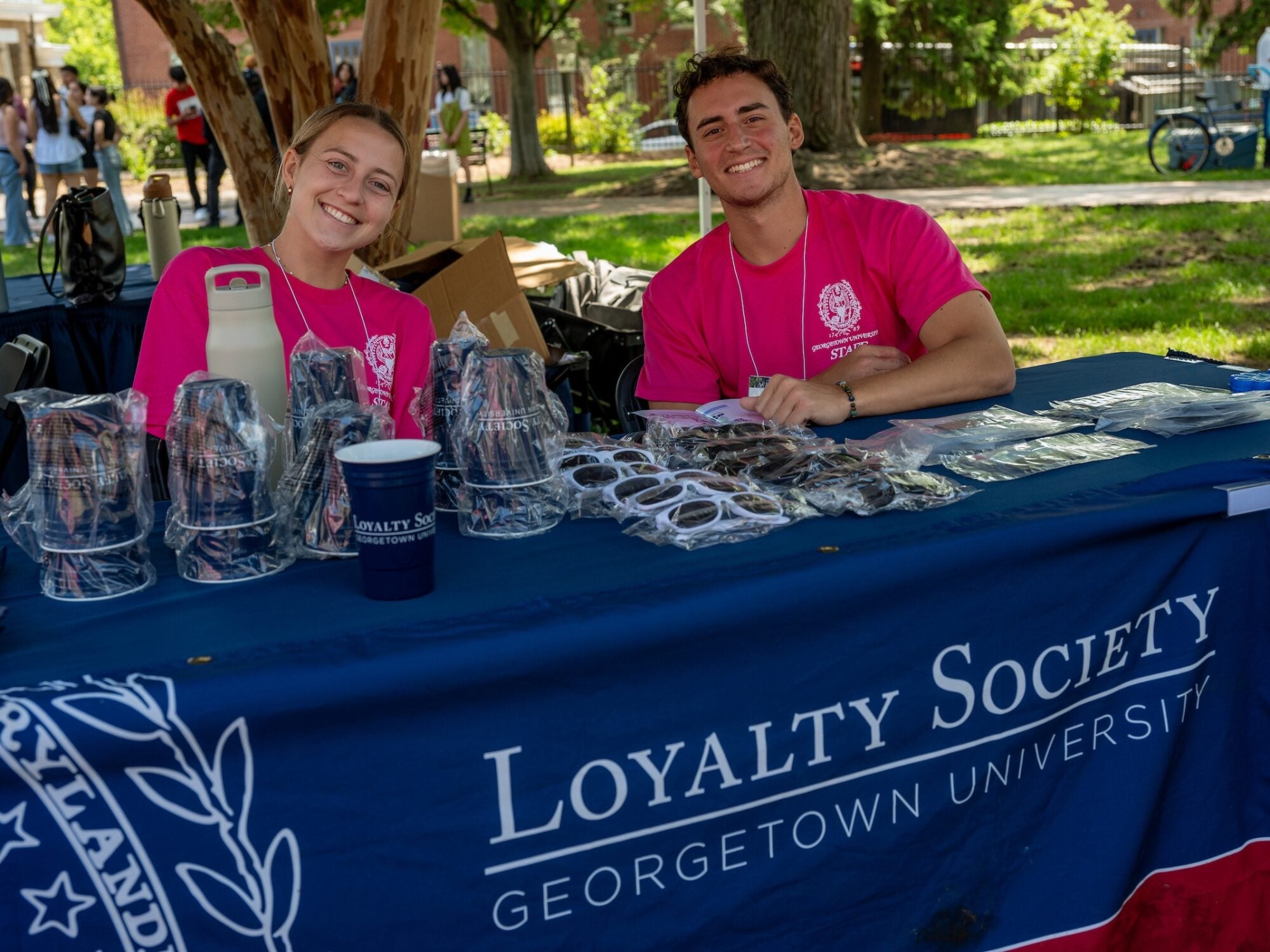 volunteers for alumni reunion sitting at a welcome table smiling